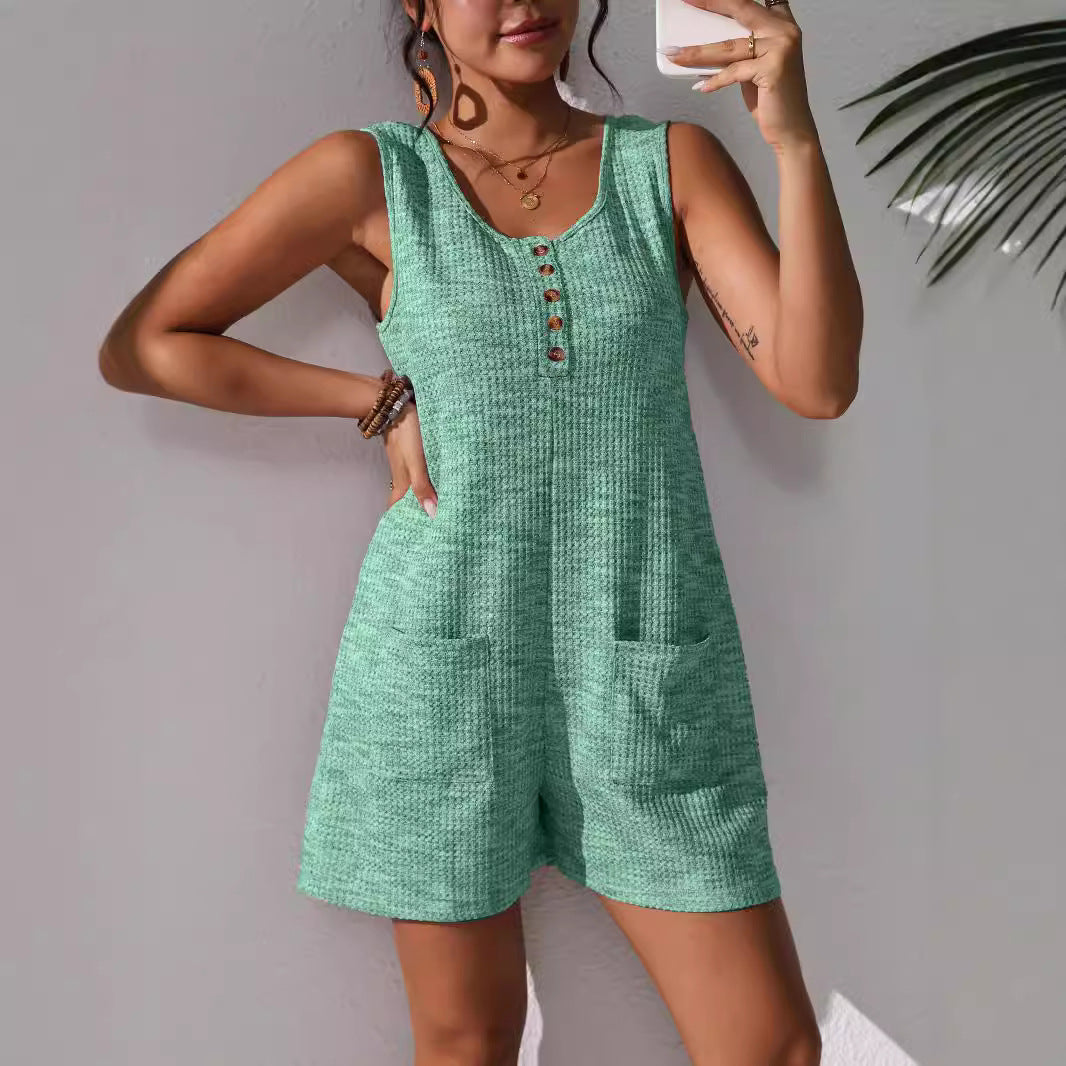 Sleeveless olive green utility vest jumpsuit featuring a button-down front bodice, structured collar, and deep patch pockets