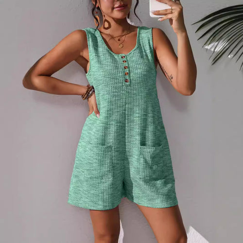 Sleeveless olive green utility vest jumpsuit featuring a button-down front bodice, structured collar, and deep patch pockets